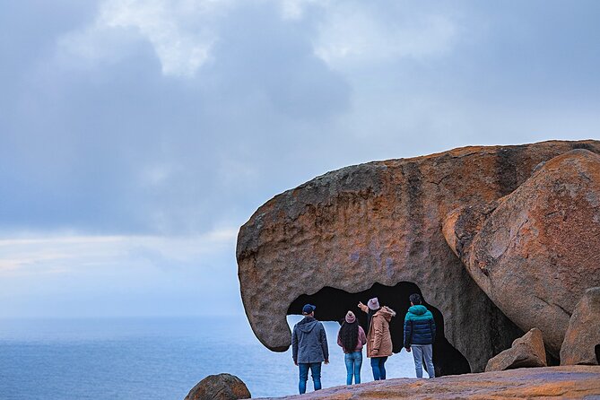 group of people standing in front of big rock
